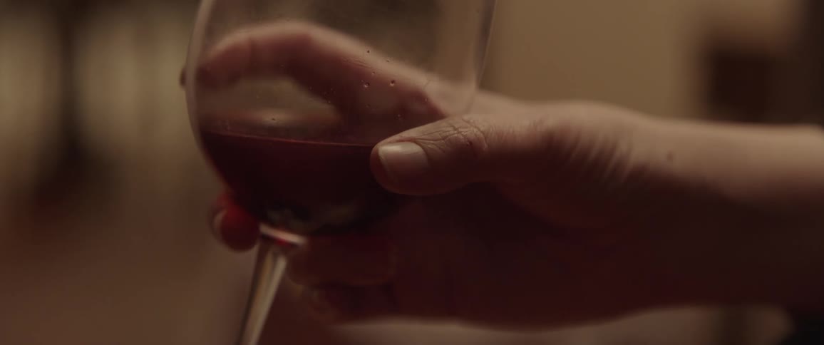 Hand holding a wine glass with red wine