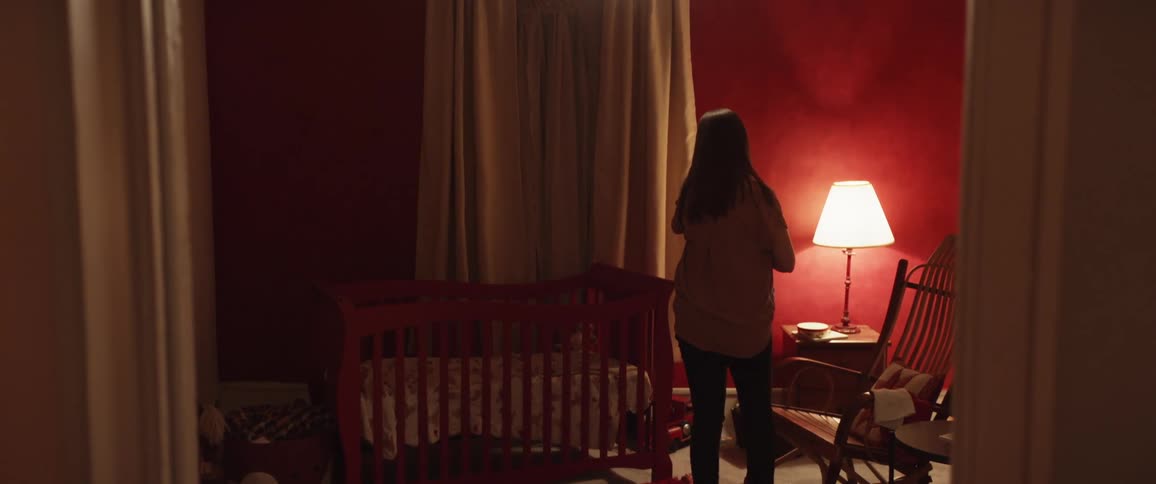 A woman stands in a babys bedroom and faces the wall