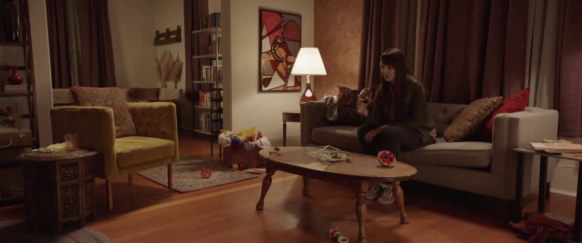 A woman is sitting on the couch drinking wine