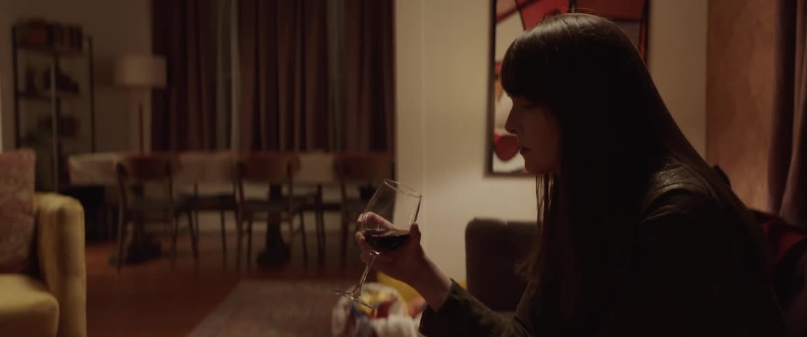 A woman is sitting on the sofa drinking wine