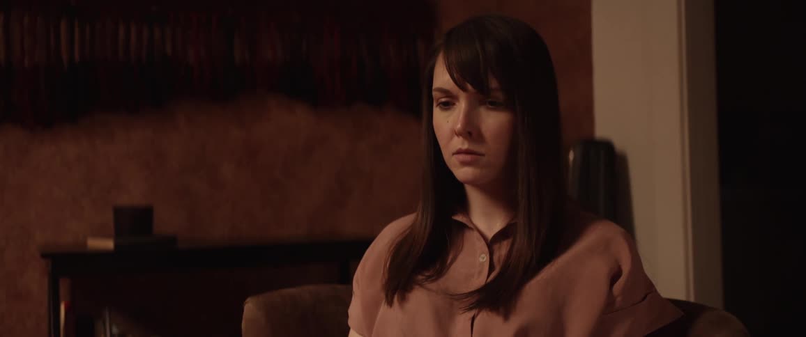 A sad white woman sits in a room in a home