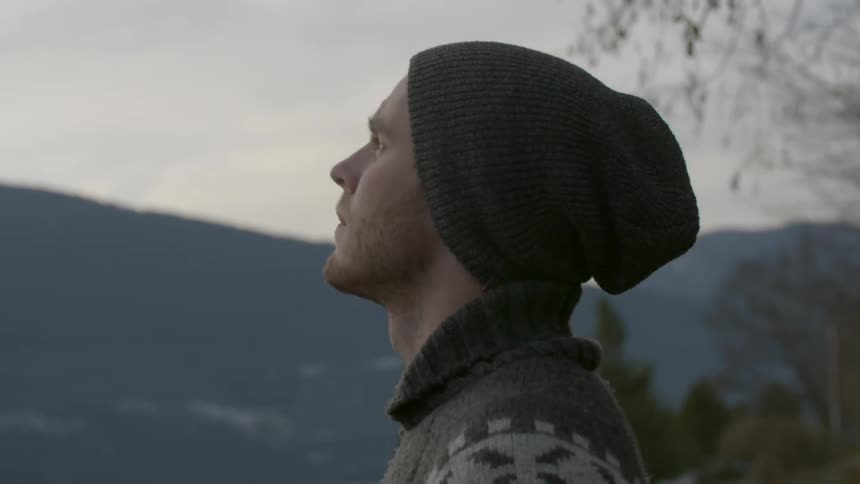 A man in a beanie looks around outside