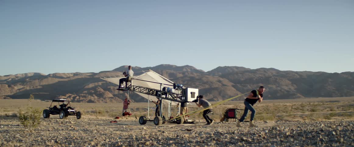People pull a crane with a person filming on top