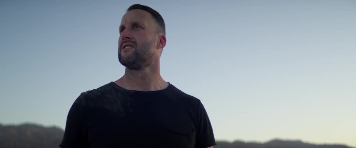 A man is standing outdoors at dusk