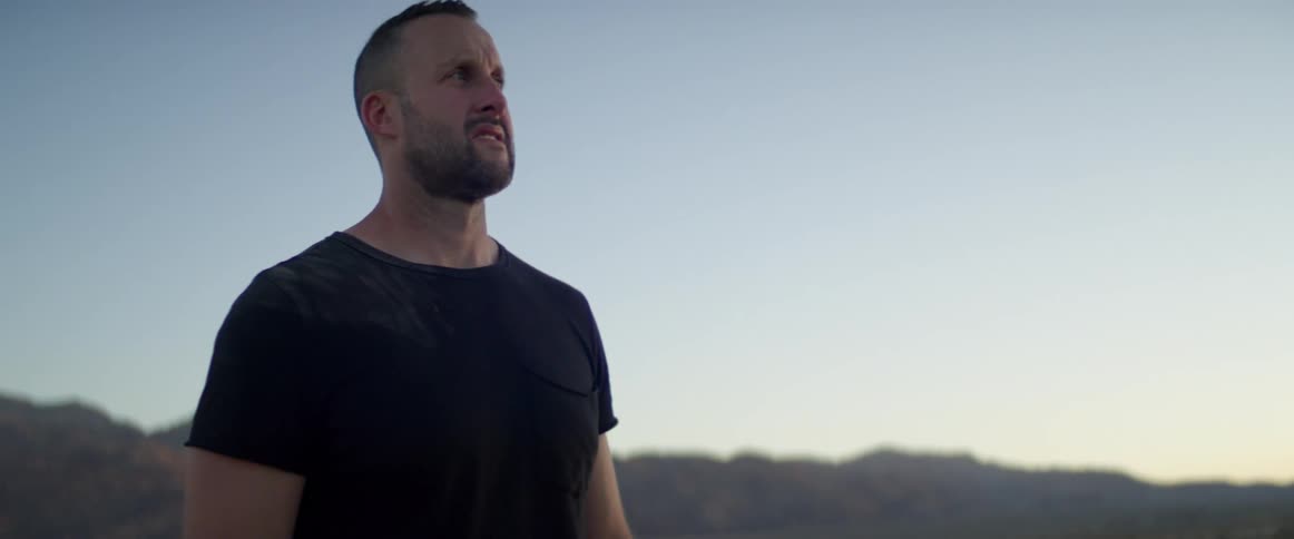 Strong muscular man looks around on the plains at dusk