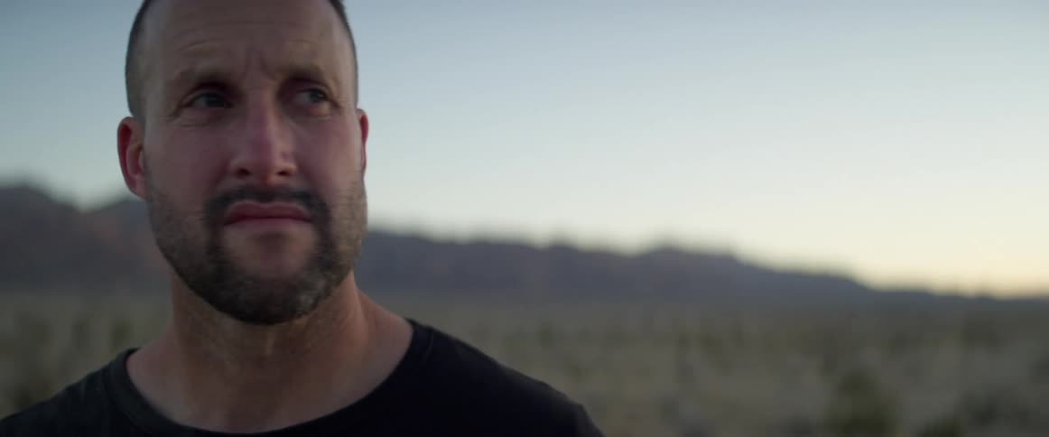 Strong muscular man looks sideways on the plains