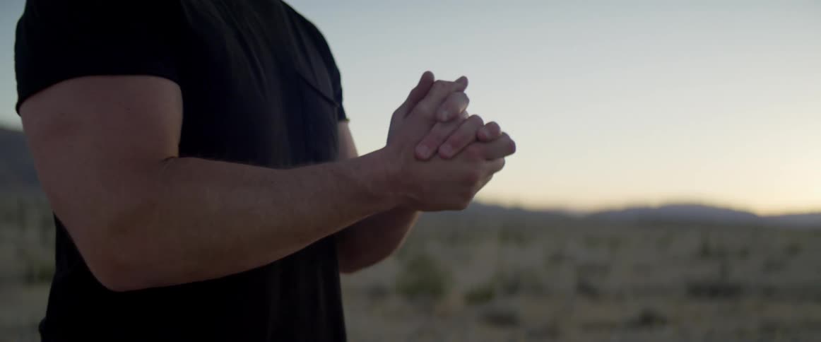 Man stretches his arms as he stands in a field
