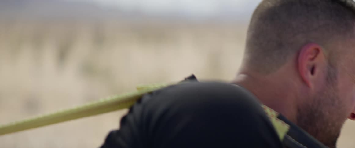 A man pulls weights behind him in a field near a mountain range