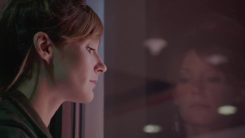 Window glass reflect face of woman standing and looking outdoors