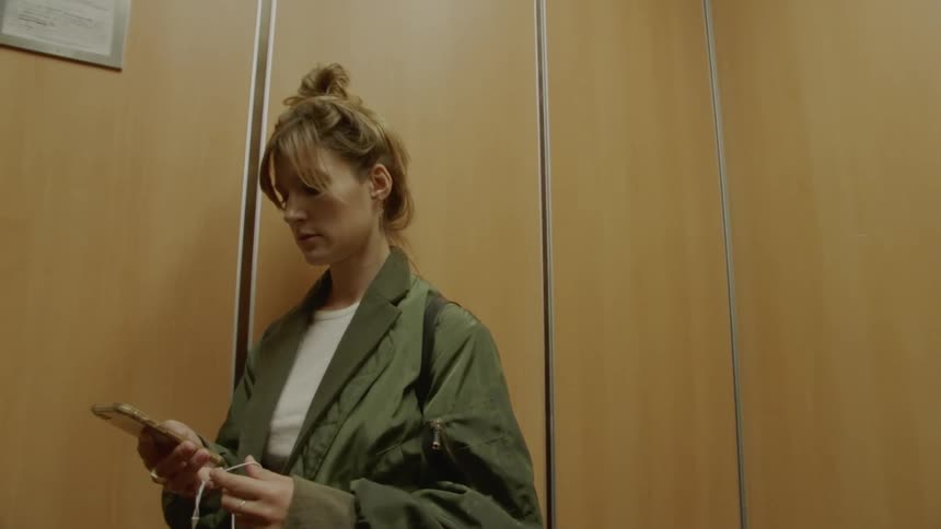 Woman plays with mobile phone until elevator arrives then enters empty office