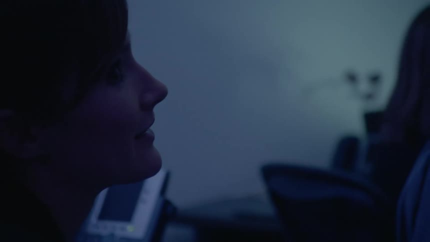 Woman talks to other people gathered in a dimly lit room