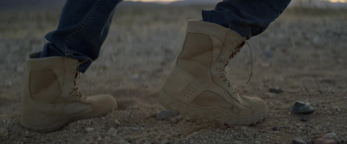 Feet of a person pushing something heavy on the desert