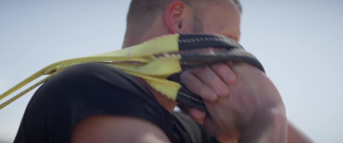 A strong white male hoists a rope and beings pulling on it