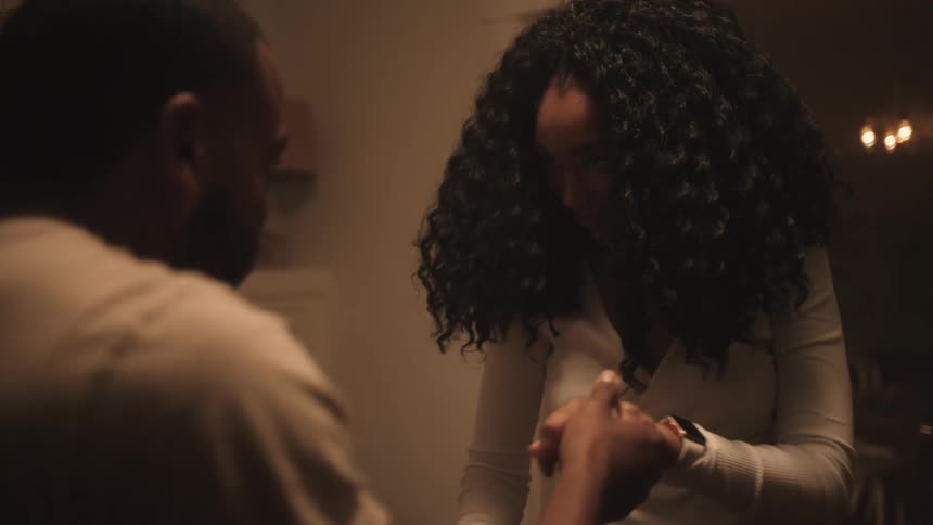 A couple holds hands as they smile and dance in their living room
