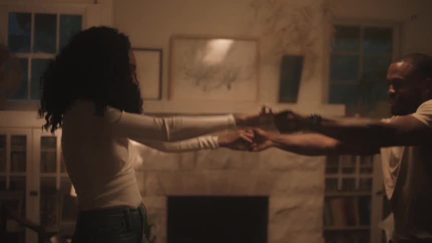 A black couple dances in the living room of a home