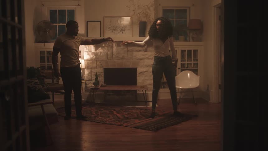Black man and woman dances together in the living room
