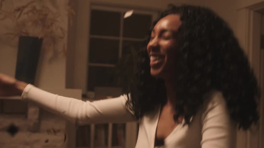 Black man and woman celebrate and enjoy themselves by throwing small confetti in the living room at home