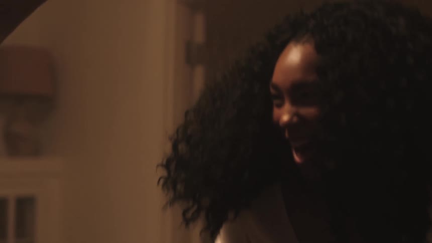 A young woman jumping and dancing in celebration in a house