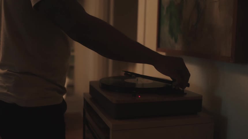 A man placing the needle of a record player on the record