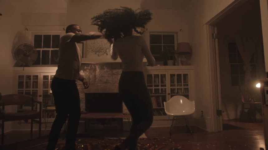 Black couple dancing and celebrating indoors in their living room at night