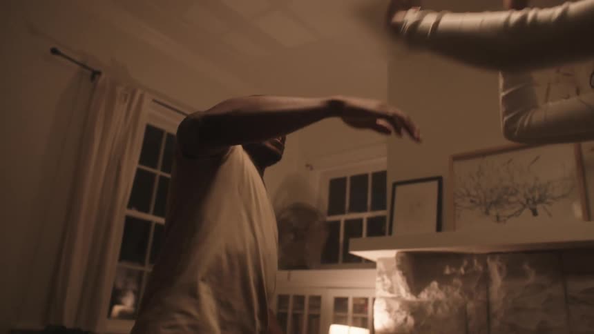 A man and woman swing their arms as they laugh and dance in their living room