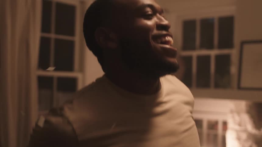 A man dancing and smiling in his living room as gold streamers and confetti fall