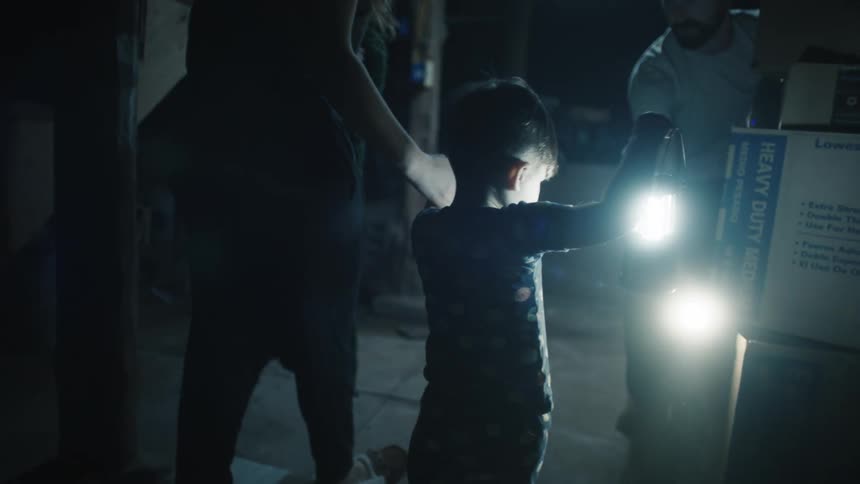 A family moves around a basement at night