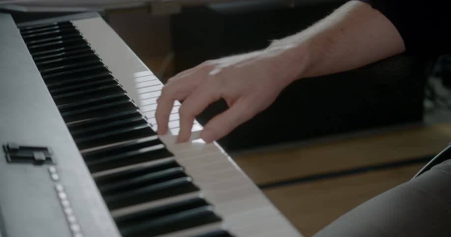 A man plays an electronic keyboards and sings near a computer workstation