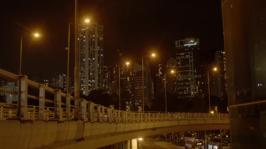 Vehicles drive on the road and overpass bridge with skyscrapers in the background at night