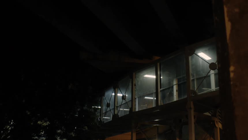 A person walks through rooms of a building with large windows at night