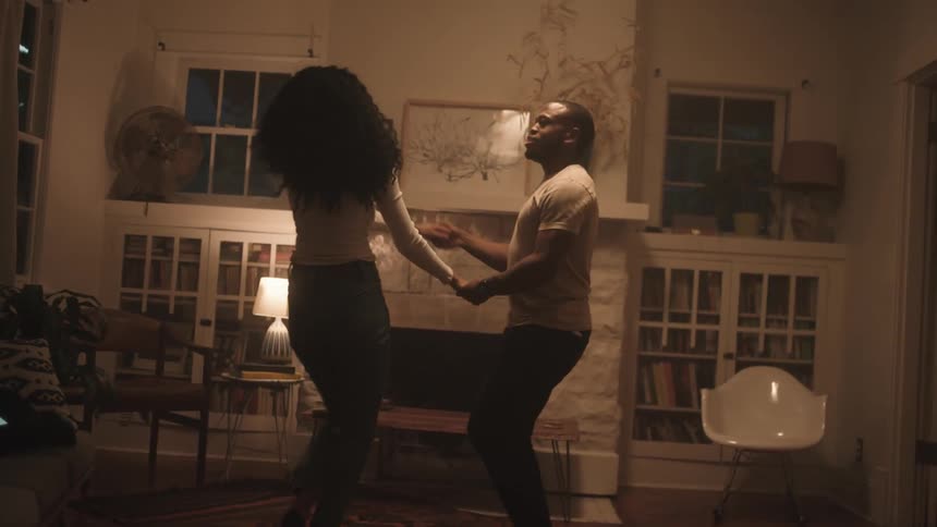 Black man and woman start dancing in the living room at home