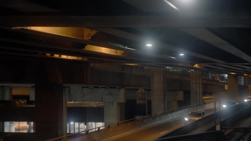 Vehicles drive on a highway ramp at night