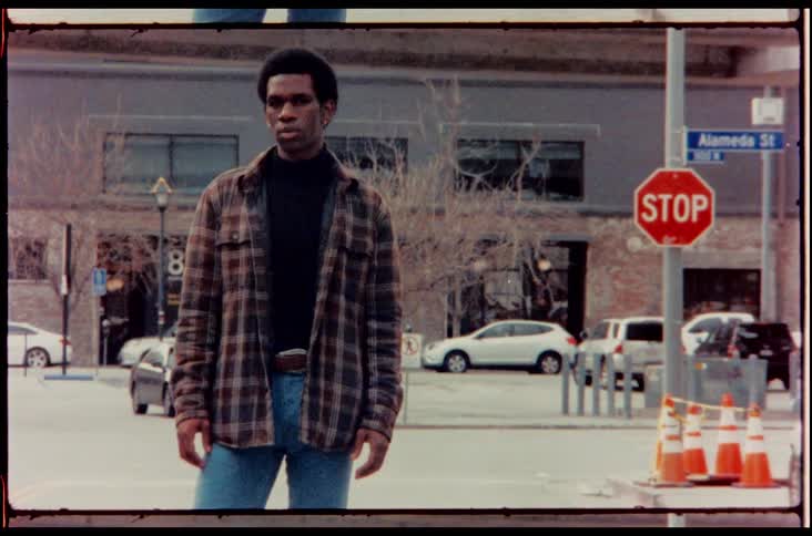 A black man posing on a city road during the day