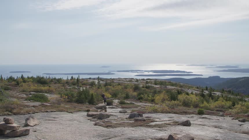 Two people walking across flatlands by the coast