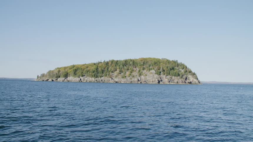 An island covered in trees sits in the middle of the ocean