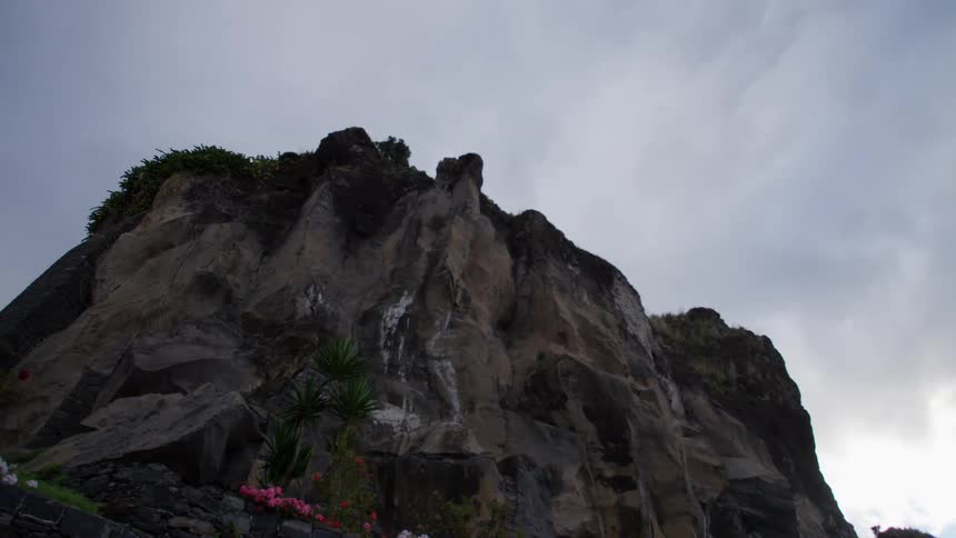 A rocky mesa with flowers growing at its base