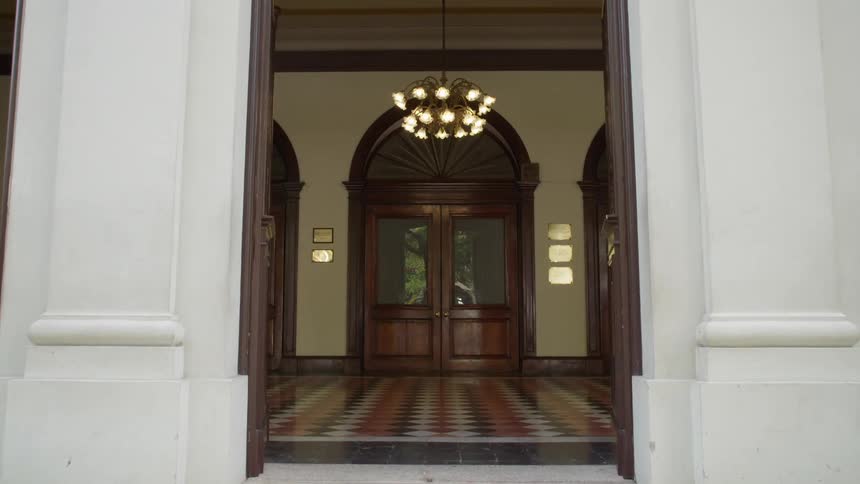 The camera passing through the first of two sets of doorways on a large building