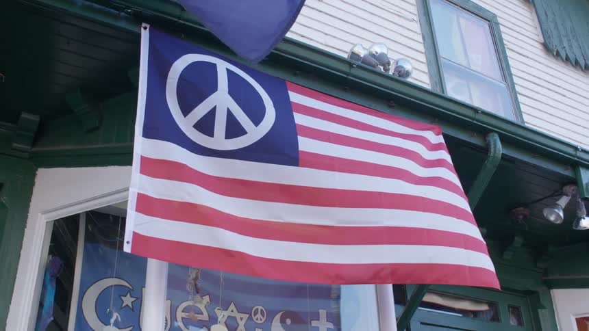 American flag with peace sign waves in storefront on small town