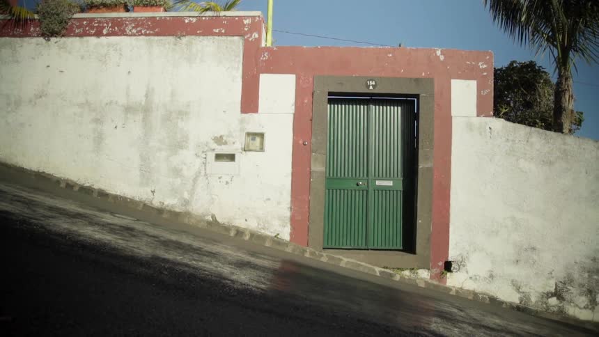 A slanted street with a wall and a door