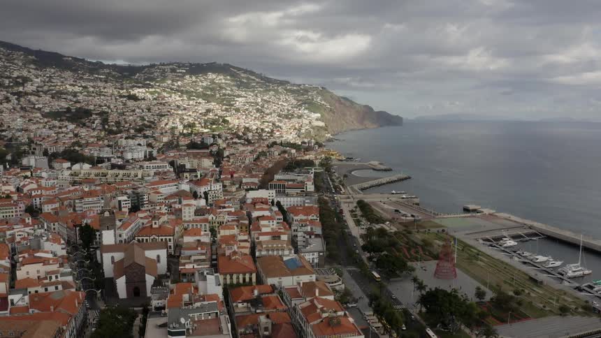 A coastal town with the ocean and mountains in the background