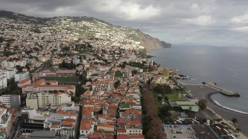 A row of buildings with red roofs near the coast in a city