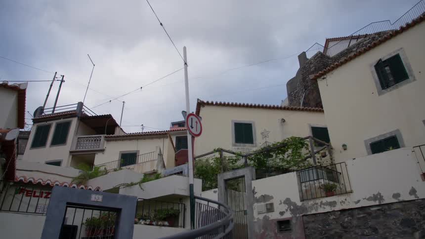 Red roofed buildings with metal gates and stone walls cluster alongside steep road