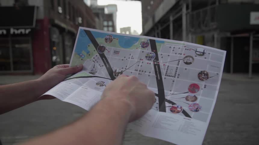 A man stands in the street and looks at a map