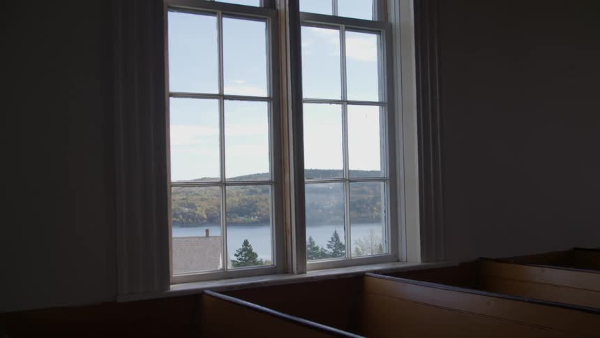 The river and trees viewed through a window above wooden pews