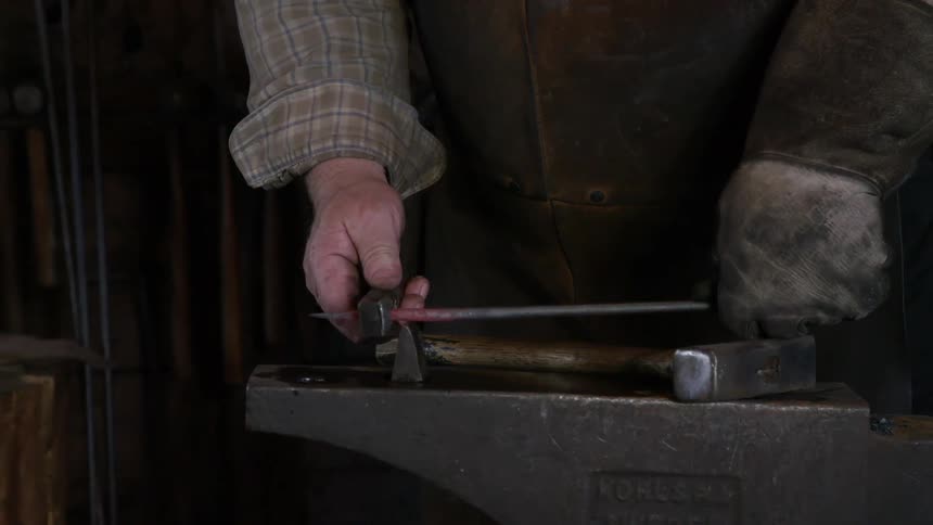 A man working with iron on top of an anvil