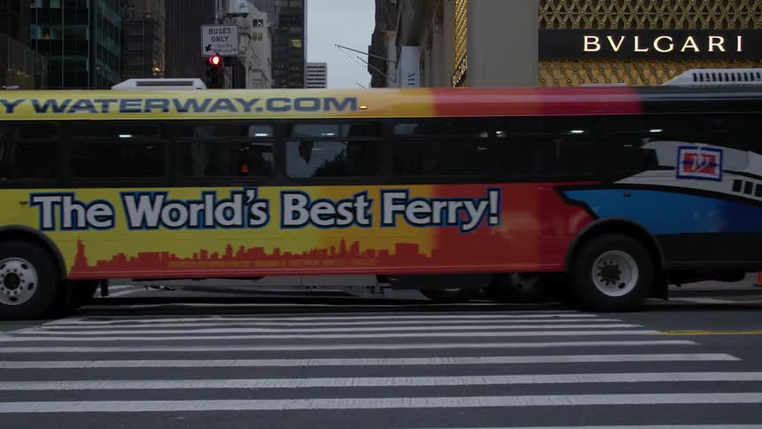Cars and buses travel through a city intersection
