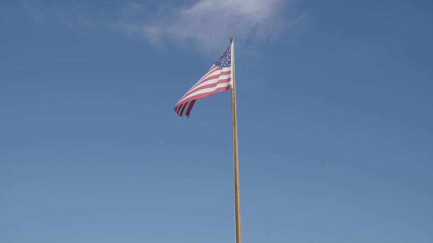 An america flag on a flag pole waving in the wind