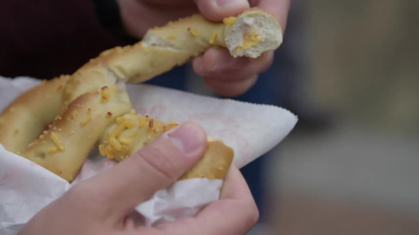 A person breaking a piece of pretzel