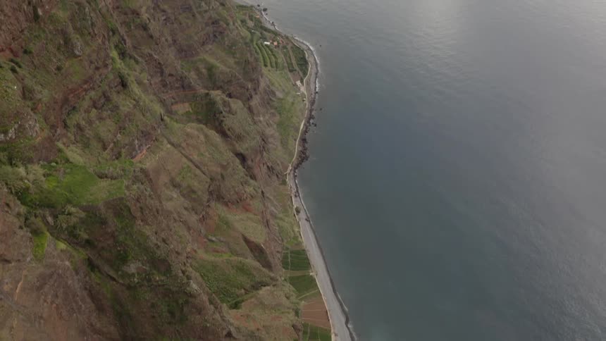 Aerial shot of a street with rocky cliffs and the ocean