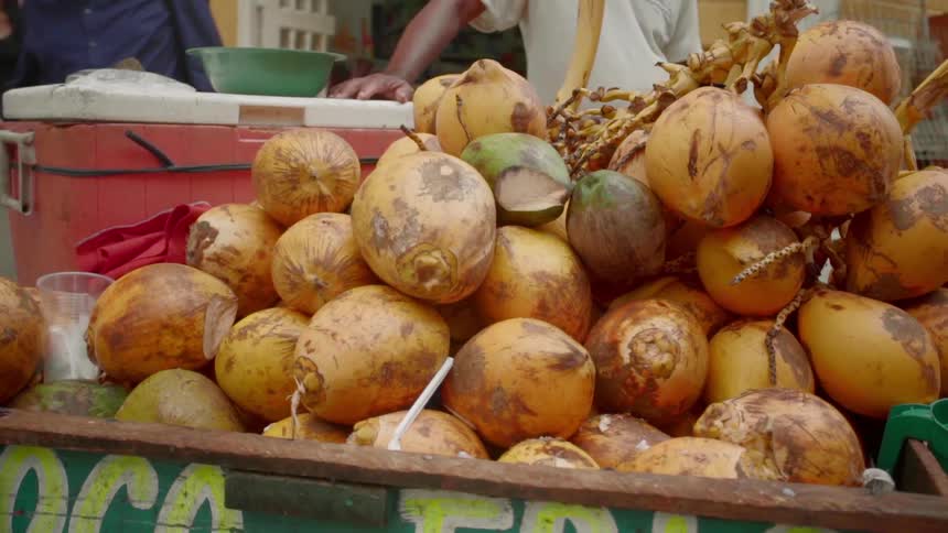 Man stands by a bin full of large onions in a street market
